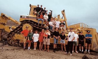 Avgangselevene ved den Tekniske Fagskolen på Gjøvik har klatret opp på en D11 dozer på ca. 98 tonn. Maskinen ble brukt under demonstrasjon på det velkjente testfeltet Caterpillar har i Malaga, Spania. Helt til venstre i bildet (på bakken) står Pay & Brincks Steinar Kjeldsen som holdt seminar for studentene i Malaga.