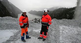 Knut Fjelldalselv (t.v) og Raymond Langfjord er skiftledere og er kun på jobb sammen til ære for A&Ts fotograf. Til høyre står «kalksteinstrålen» fra knuseverket. Steinen tas videre på transportbånd til skipet nedenfor.