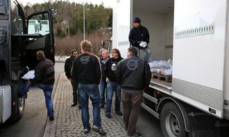Per Danielsen fra Volvo Norge deler ut kjettinger til alle bilene ved tollstasjonen. Samlet vekt på kjettingene er over to tonn.