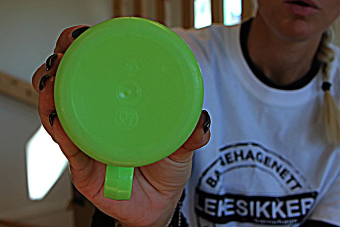 Prosjektleder i "Lekesikker barnehage", Turi Dolve Lund, holder opp en plastkopp som er merket med bestikk for å vise at det er egnet å spise med og på.