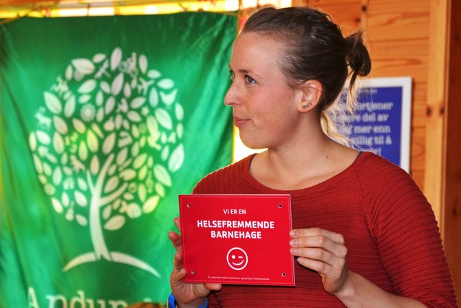 Folkehelsekoordinator i Andøy kommune, Katja Larsen, med skiltet som skal henges opp i barnehagen.