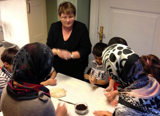 Barna fra Refstad transittmottak baker boller sammen med daglig leder Birgit Somby.