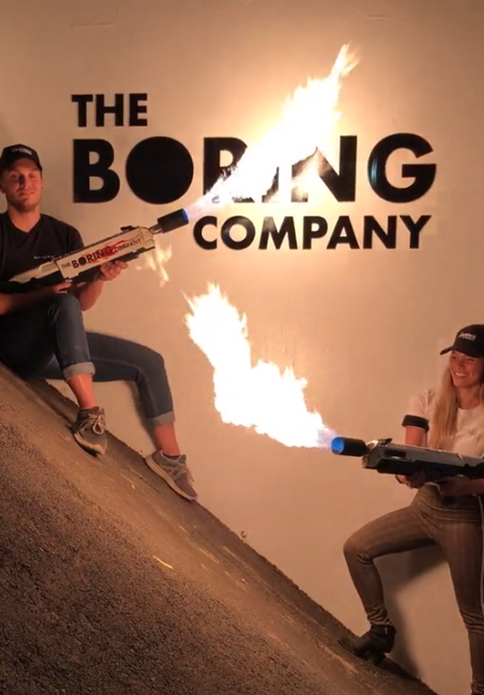 To personer holder hver sin flammekaster foran logoen til The Boring Company.