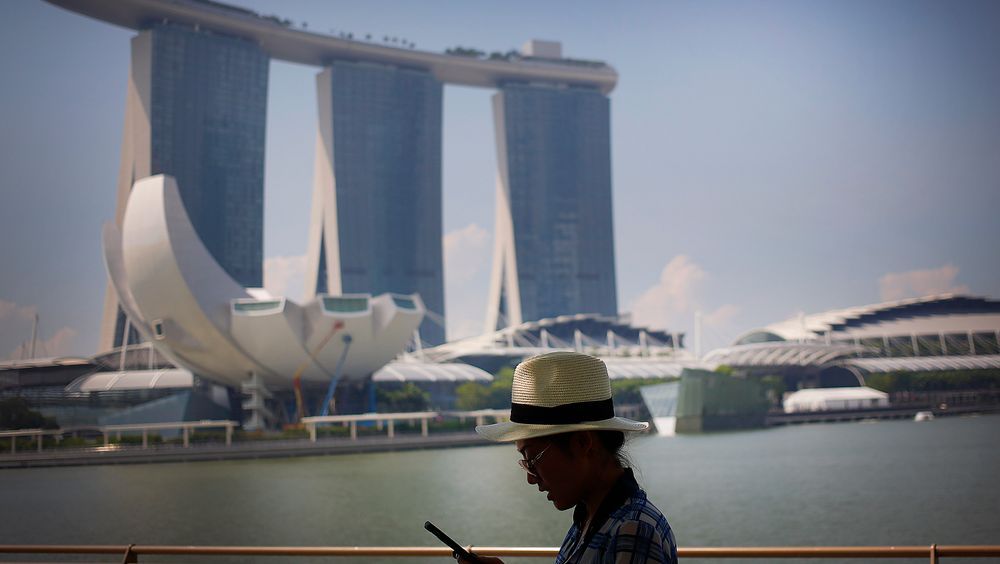 En turist sjekker smarttelefonen i Marina Bay Sands, Singapore. Byen er på topp i smartbyundersøkelser. Men på noen områder ligger Norge foran.