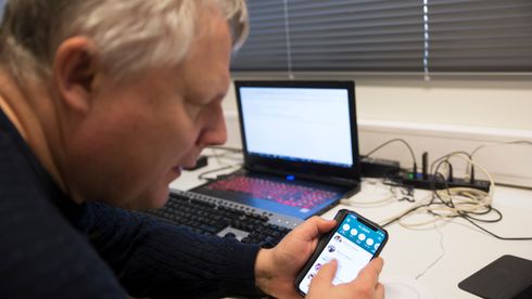 Morten Tollefsen med mobiltelefon i hånda, med Vipps-appen åpen. Foto.