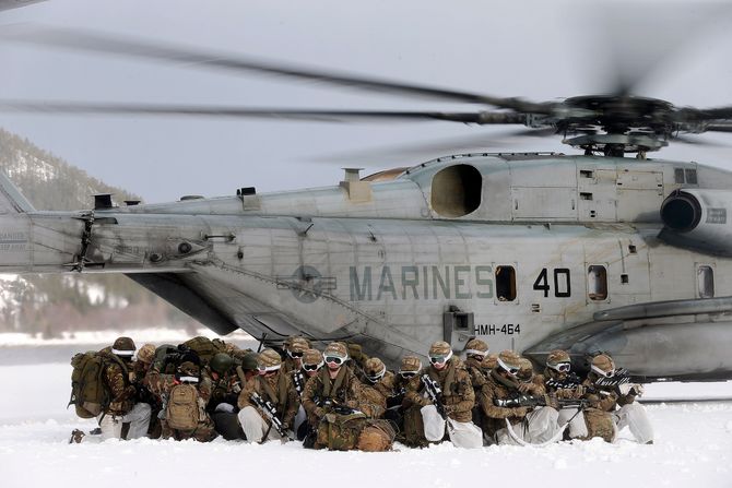 Nederlandske marine infanterister sitter i kringvern på bakken da to Amerikanske CH-53E Super Stallion helikopter tar av under vinterøvelsen Cold Response 2016.