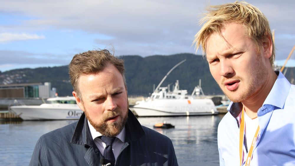 Eirik Hovstein i Maritime Robotics forteller ministeren at klyngesamarbeidet i Trondheim er viktig, men at det også er tøff konkurranse. En av Kongsberg Seatex' autonome livbåter, og Maritime Robotics' lille Oteren sees på vannet i bakgrunnen.
