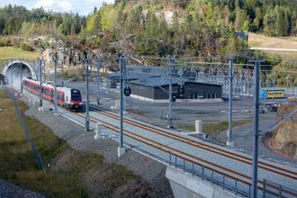 Tog som kommer ut av Nøklegårdtunnelen og passerer Solum omformerstasjon