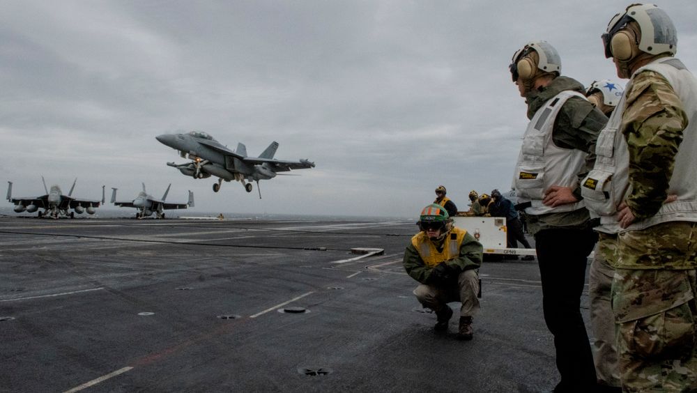 NATOs generalsekretær Jens Stoltenberg ser på mens et F-18 Super Hornet-fly lander på det amerikanske hangarskipet USS Harry S. Truman, som skal delta i NATO-øvelsen Trident Juncture.