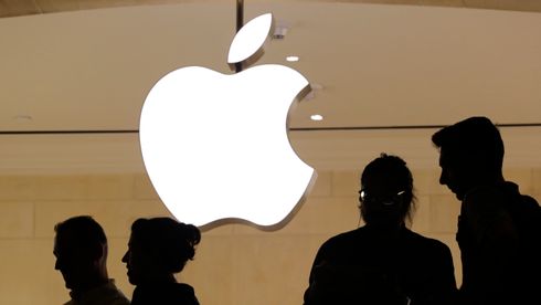 Silhuetter av mennesker foran en stor Apple-logo.