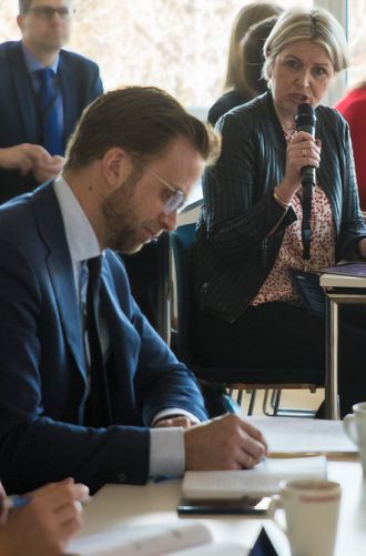 Nikolai Astrup noterer mens Kristin Vinje snakker til ham i bakgrunnen.