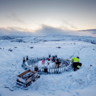 En elektriker arbeider med fundamentet til en vindturbin i Roan vindpark i desember. Fjelltoppen er dekket av snø.