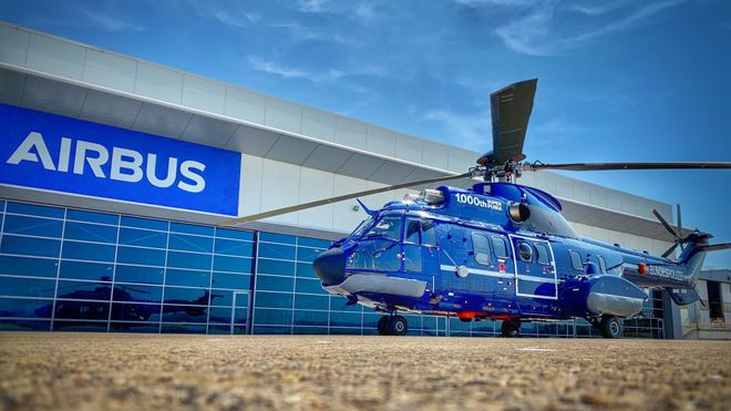 Et helikopter parkert utenfor en bygning med stor Airbus-logo