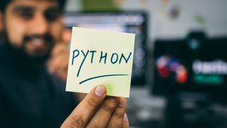 Mannlig utvikler holder opp en gul lapp med skriften "Python".