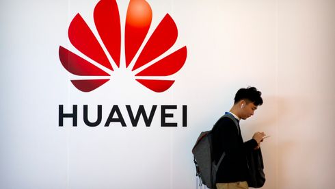 Mann trykker på en telefon foran en Huawei-logo. 