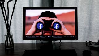 PC-skjerm. På skjermen vises en person som ser på deg med en kikkert med Facebook-logoen.