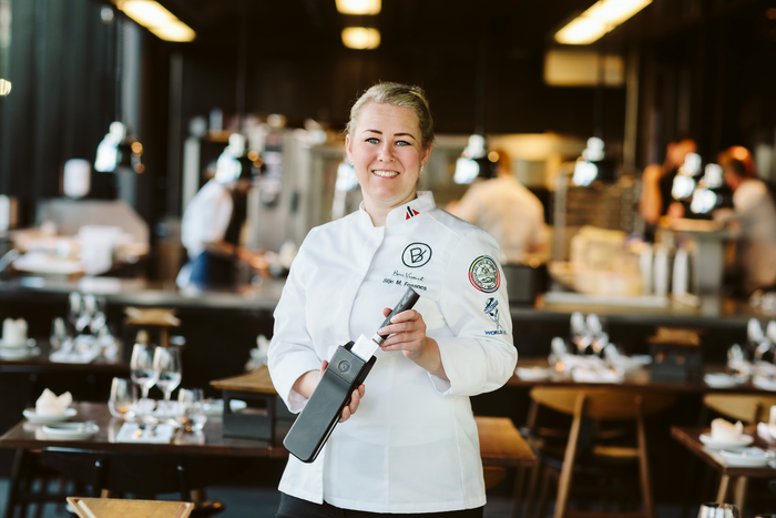 Bilde av Silje Merete Fossnes, grunnlegger av Bon Vivant, avbildet i en restaurant, mens hun holder hennes patenterte knivslire