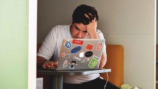 Frustrert eller stresset utvikler med masse koderelaterte klistremerker på laptopen.