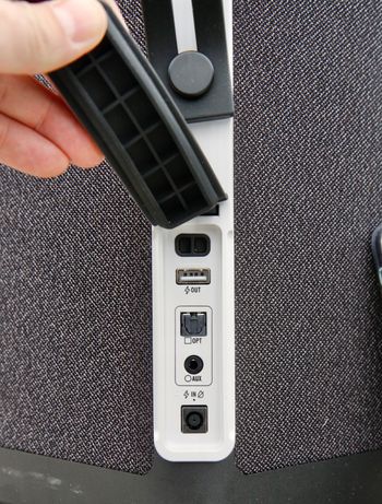 Under et gummideksel finner du tilkobling for eksterne lydkilder (både optisk og analog), samt en USB-kontakt som lar deg lade mobiltelefonen.