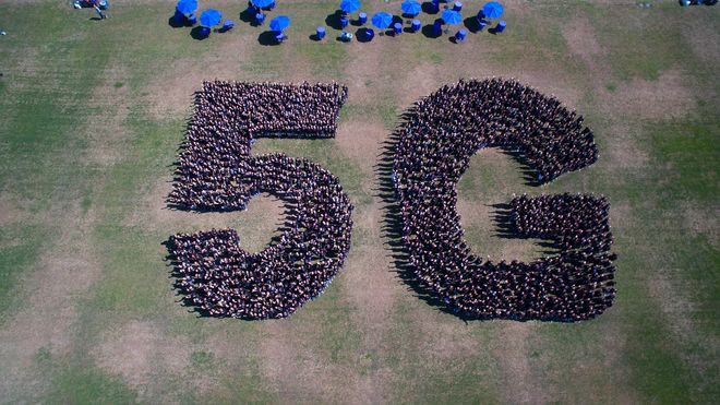 Et stort antall mennesker danner bokstavene 5G.