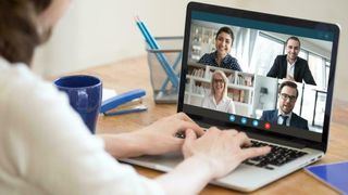 Kvinne foran digitalt møte med fire personer på laptopskjermen. 