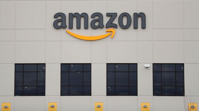 Amazon-logoen i svart og oransje på en bygning med svarte og oransje detaljer.