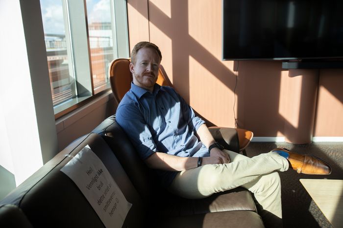 Aslak Ege sitter i en sofa på kontoret, der annet hvert sete er sperret av hensyn til smittevern.