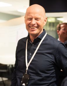 Per Gunnar Tronsli i midten av bildet, leende, med en mann med ryggen til kameraet på hver side.