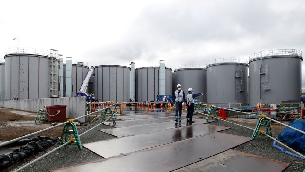 Arbeidere på kjernekraftverket Fukushima Daiichi, som eies av Tokyo Electric Power. Arbeidet med å avvikle det ødelagte atomkraftverket pågår. I bakgrunnen står tankene med radioaktivt vann.