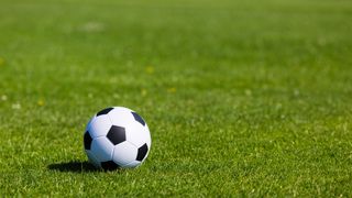 Nærbilde av en fotball på gresset til en fotballbane. 