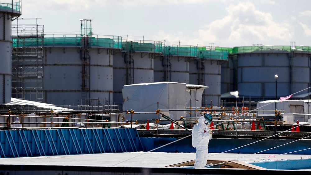 En arbeider står foran tanker fylt med radioaktivt vann ved Fukushima DaiIchi kjernekraftverk. I dag er det ti år siden ulykken.