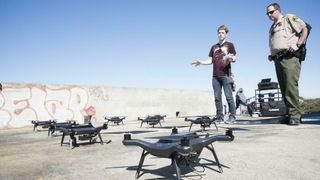 to personer ser på mange droner som står på bakken. Sondre Andreas Engebråten til venstre.