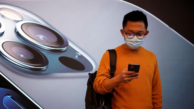 En mann bærer ansiktsmaske mens han venter i en Apple Store i Shanghai, Kina ved lansering av Iphone 12 i fjor høst.