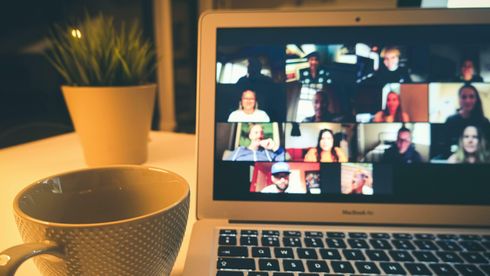 Foto av skjermmøte på Mac med kaffekopp og plante ved siden av 