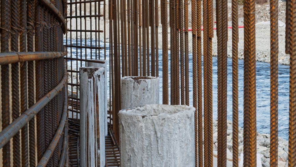 Enkelte steder er lite plass mellom eksisterende bygg og elveløpet, som her. Da må det bygges en solig mur, pelene er boret minimum to meter ned i solid fjell, og forankrer muren som etter hvert blir støpt.