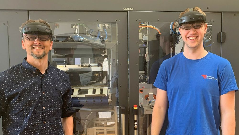 Eivind Adelsten Rosén og Andreas Thoresen med "HoloLens" foran en pakkemaskin.