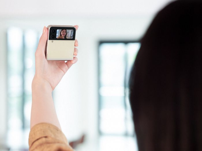 Kvinne tar selfie med lukket klapptelefon