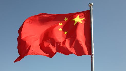 Kinesisk flagg som vaier foran blå himmel