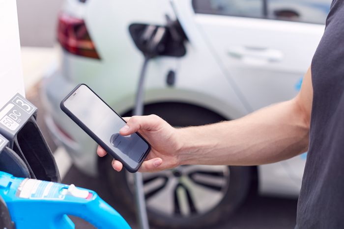 man leser på mobilen mens bilen lades.