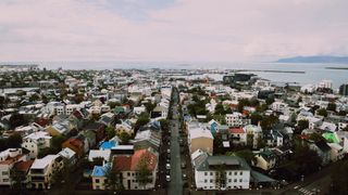 Foto tatt over hustakene i Reykjavik med havet bak