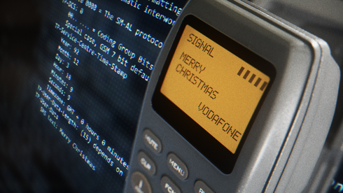 En gammel telefon med teksten MErry Christmas foran en mer moderne skjerm med kode