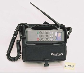 En gammel telefon på et hvitt bord. Telefonen har egen veske og et rør man løfter av og en stor lang antenne