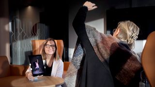 Fysioterapeut Lina Lindegaard holer frem ipaden foran en eldre kvinne som gjør øvelser.