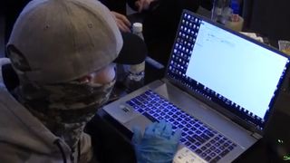 Maskert FSB-agent studerer PC beslaglagt fra hackergruppen Revil.