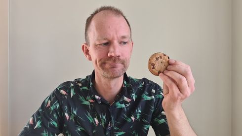 Portrettfoto av Jørgen Brunborg-Næss som holder en sjokoladekjeks i hånden som han titter skeptisk på