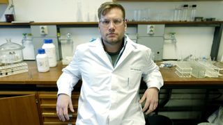 Sandtorv i laboratoriet med hvit frakk og vernebriller.