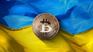 En bitcoin-mynt foran et ukrainsk flagg.