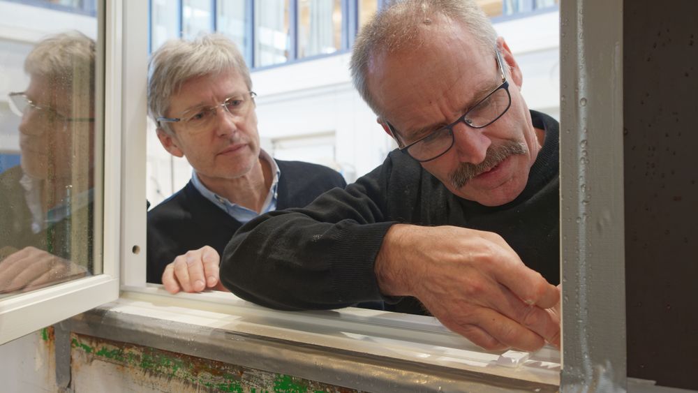 Tor Lømo-Hansen (t.v.) og Gjermund Horten forsøker å se hvor lekkasjene har oppstått som følge av det harde regnet prototyp-vinduet ble utsatt for.