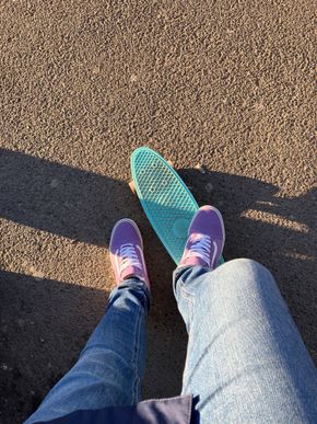 Bilde av lilla sko på turkist skateboard på asfalt