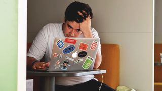 Frustrert eller stresset utvikler med masse koderelaterte klistremerker på laptopen.